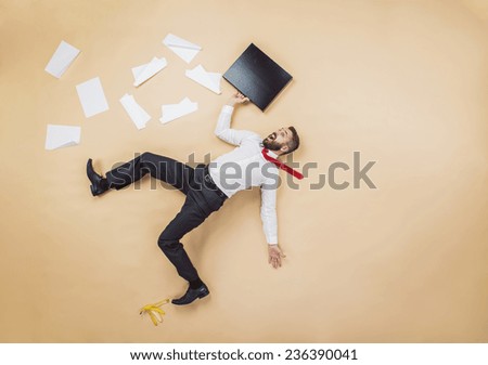 Handsome manager having an accident. Studio shot on a beige background. Funny pose.