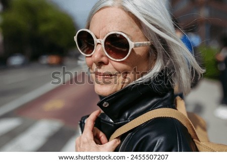 Similar – Foto Bild Stilvolle Frau mit Sonnenbrille posiert an Graffiti-Wand auf Stadtstraße.