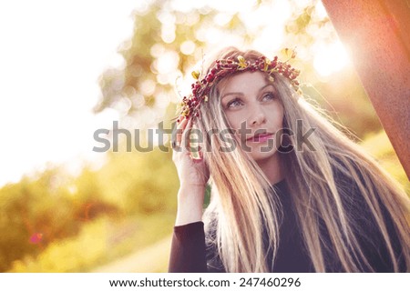 Attractive young woman with wreath of berries on her head with sunset in background.