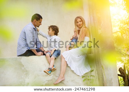 Happy young family spending time together sitting outside on a porch of old house.