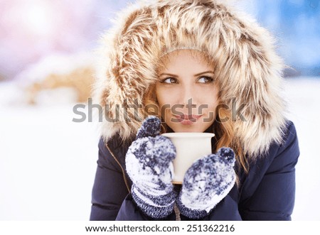 Attractive young woman outside in snow with a cup of coffee