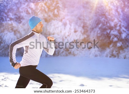 Young sportsman jogging outside in sunny winter park