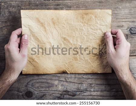Piece of old rumpled paper on wooden floor background