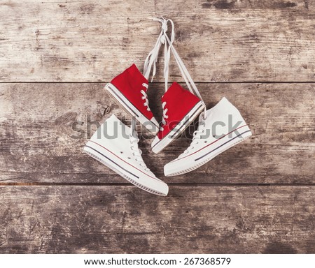 Two pairs of sports shoes hang on a nail on a wooden fence background