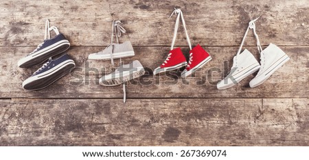 Four pairs of sports shoes hang on a nail on a wooden fence background