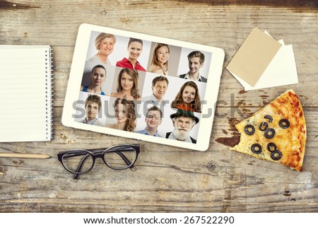 Desktop mix with office gadgets, supplies and pizza on a wooden office table background. View from above.