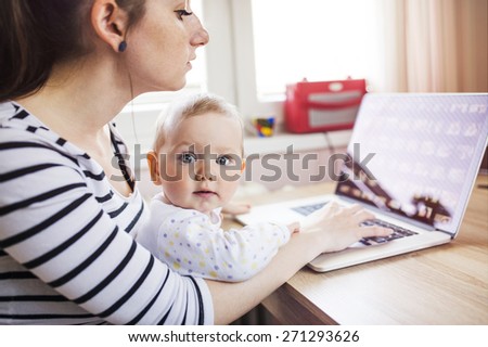Young mother in home office with computer and her daugher