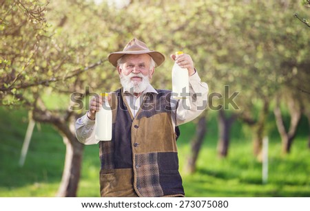 Senior farmer with milk bottles outside in green nature