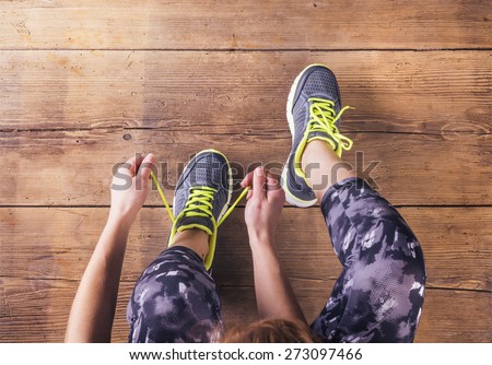 Unrecognizable young runner tying her shoelaces. Studio shot on wooden floor background. Stock fotó © 