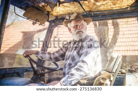 Senior man at the farm driving an old tractor