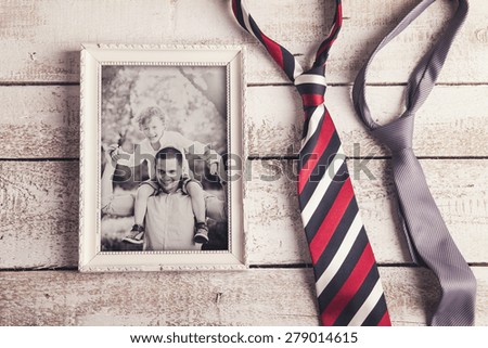 Picture frame with family photo and two ties laid on wooden backround.