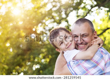 Happy father with his son spending time together outside in green nature.