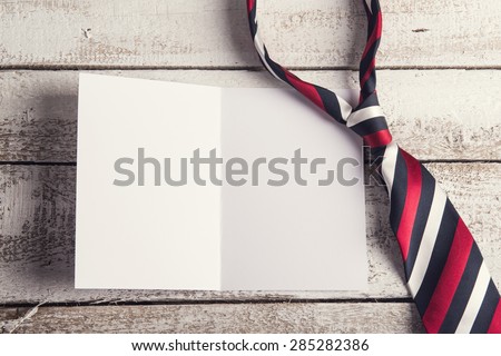 Fathers day composition - tie and empty sheet of paper. Studio shot on wooden background.