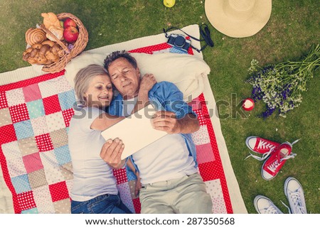 Beautiful seniors with notebook having a picnic in nature