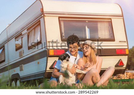 Beautiful young couple in front of a camper van on a summer day