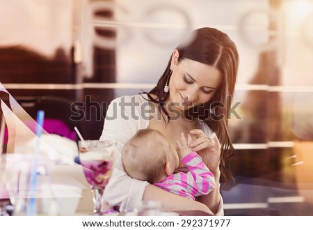 Mother breast feeding her little daughter in a cafe