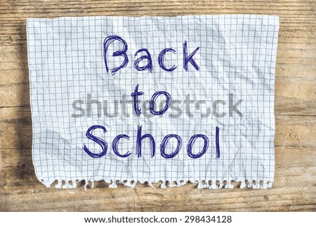 Piece of old rumpled paper with Back to school sign on wooden floor background