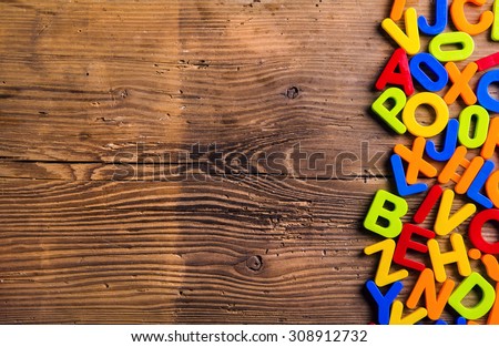 Colorful plastic letters and numbers laid on wooden background.