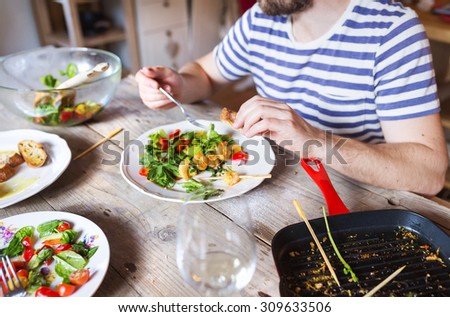 Unrecognizable man eating prawns, salad and bread together