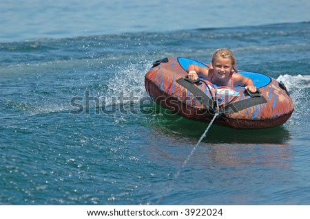 Smiling Girl Water Tubing Over a Wave