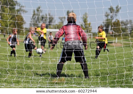 Young Soccer Goalie from Behind Goal Netting