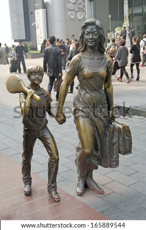SHANGHAI, CHINA-15 OCT.2013 Bronze statue of a woman with child. Nanjing Road is the main shopping street of Shanghai and is one of the world\'s busiest shopping streets.
