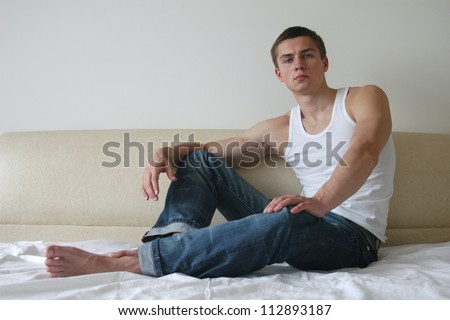 Young sexy men sitting on a bed in a bedroom