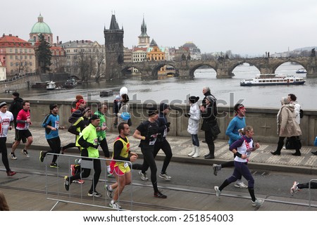 PRAGUE, CZECH REPUBLIC - APRIL 6, 2013: Athletes run over the Manes Bridge on the Vltava River during a marathon run in Prague, Czech Republic. The Charles Bridge is seen in the background.