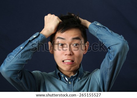 Disappointed young Asian man making face and looking sideways
