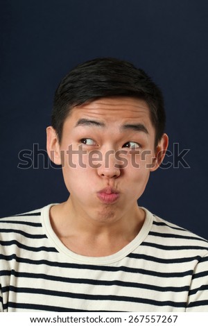 Funny young Asian man making face and looking sideways