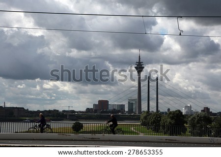 DUSSELDORF, GERMANY - AUGUST 6, 2012: Bikers go in front of the Rheinturm or the Rhine Tower in the Medienhafen District in Dusseldorf, North Rhine-Westphalia, Germany.