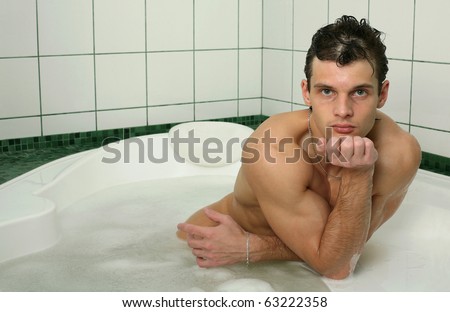 Young muscular man taking bath