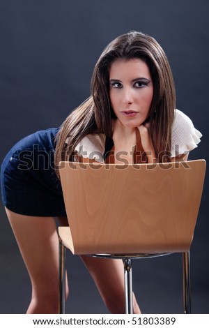 Attractive young woman bending over the chair and leaning her head on her hands.Side view.