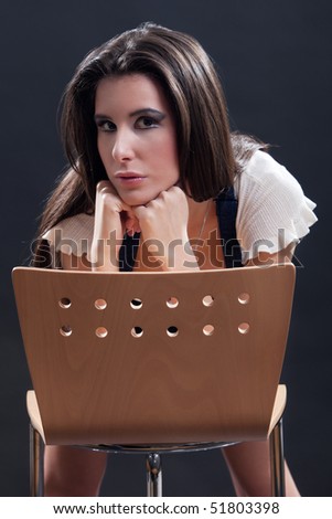 Attractive young woman bending over the chair and leaning her head on her hands.