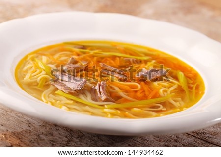 Beef broth with vegetables, noodles and meat.