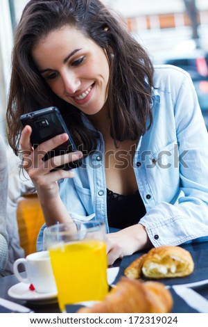 Cute young woman chatting with their smartphone at coffee shop
