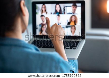 Back view of business woman making video call and showing thumb up to laptop on the online briefing while sit on sofa at home. Сток-фото © 