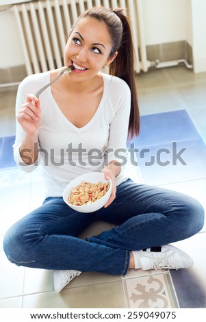 Portrait of beautiful young woman eating cereals at home.