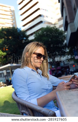 Portrait of beautiful young woman using her mobile phone in a restaurant terrace.