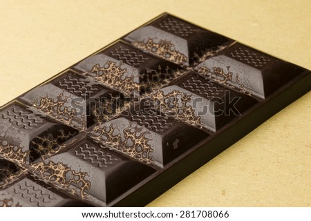 Artisanal chocolate bar with dried fruits and emerging geometric shapes of cocoa butter