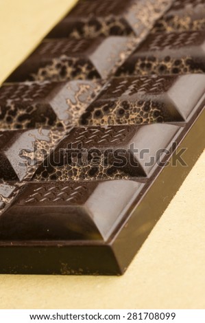 Artisanal chocolate bar with dried fruits and emerging geometric shapes of cocoa butter