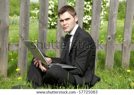 businessman in lotus pose working on laptop in country and sad