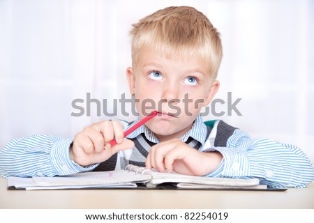 schoolboy sitting at a desk with a notebook and thinking how to do the job. boy with a thoughtful face
