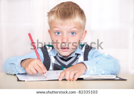 schoolboy sitting at a desk with a notebook and thinking how to do the job.