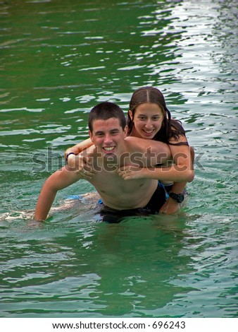 Brother carrying sister piggyback in pool