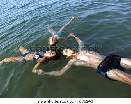 Three children back-floating in the sea creating a geometrical star