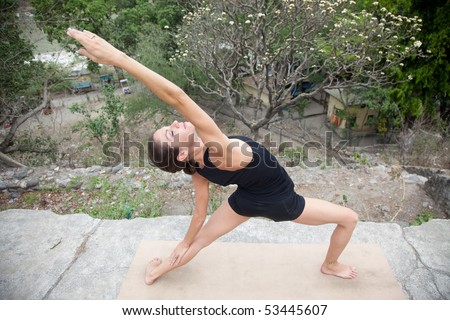 Female yoga teacher executing postures (asanas) at an old hotel in Rishikesh, India.