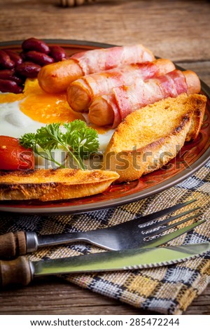 Full English breakfast with bacon, sausage, fried egg and baked beans.