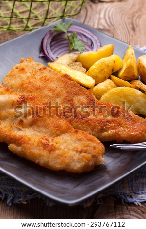 Fried fillet of cod with french fries on a dark plate. The selected focus point.