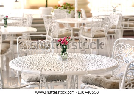 A bouquet of roses in a vase on a table in a summer cafe